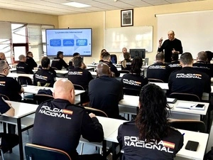 Un aula llena de agentes con uniformes de policía escucha a un hombre vestido con jersey oscuro.