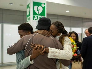 Tres personas se abrazan en un aeropuerto