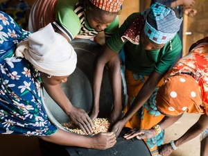 Cuatro mujeres, de Nigeria y de Níger, maniobran con una olla con granos para elaborar crema de maní