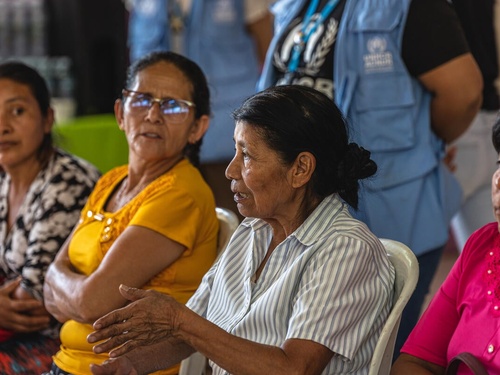 Cuatro mujeres, sentadas una al lado de la otra. Una de ellas está hablando, mientras el resto la escucha.
