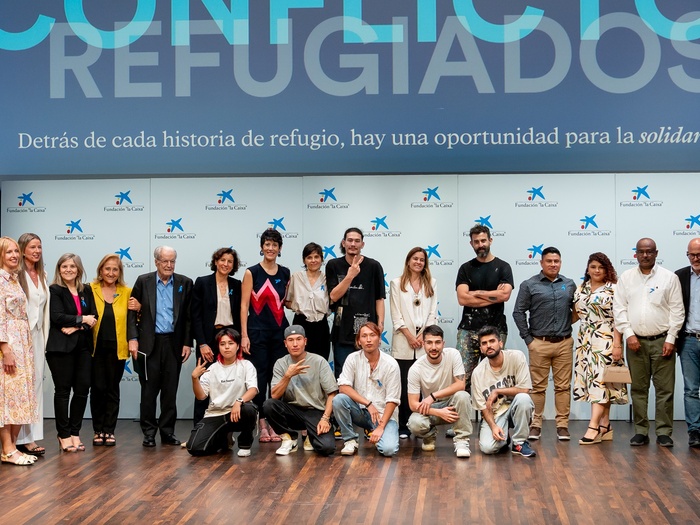 Autoridades y participantes en el evento del Día Mundial del Refugiado en Madrid posan en el escenario del auditorio de CaixaForum.