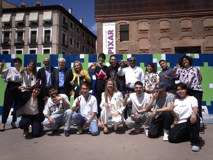 Autoridades y participantes en el evento de ACNUR con motivo del Día Mundial del Refugiado posan frente al mural solidario de Boa Mistura. 