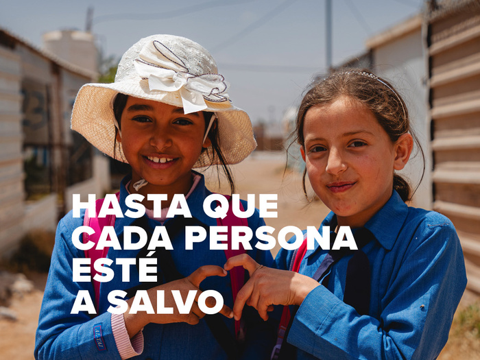 Dos niñas vestidas de azul forman un corazon con sus dedos. Se lee HASTA QUE CADA PERSONA ESTÉ A SALVO