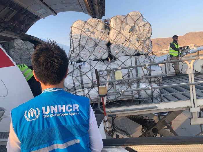 Un trabajador de ACNUR, que está dando la espalda a la cámara, observa cómo se descarga ayuda humanitaria de un avión que acaba de aterrizar en Kabul, la capital de Afganistán.