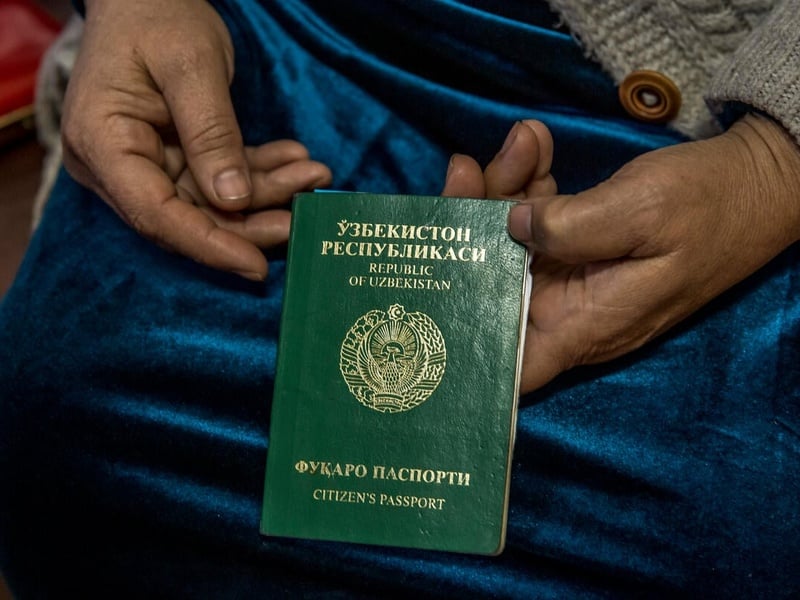Enfoque de las manos de una mujer que sostiene un pasaporte inválido de Uzbekistán