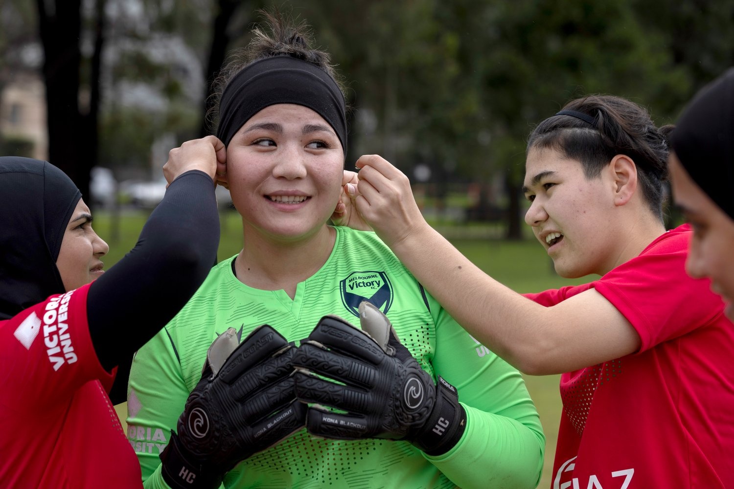 Dos chicas en uniforme ayudan a su compañera a ajustar la banda que lleva en el cabello.