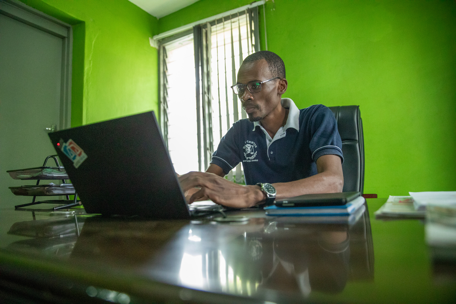 Un hombre sentado en la mesa de una oficina, trabajando con una computadora portátil.