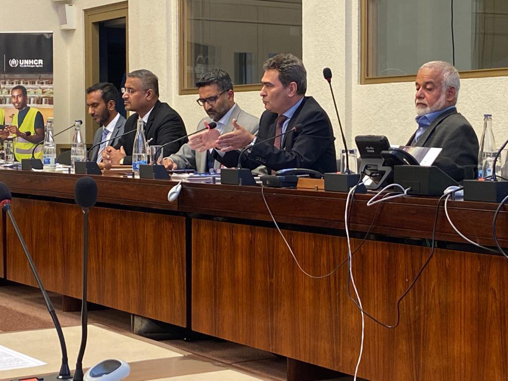 Un grupo de cinco hombres vestidos de traje sastre en un panel en el que hablan al micrófono; entre ellos, Jamal Al-Nouri.