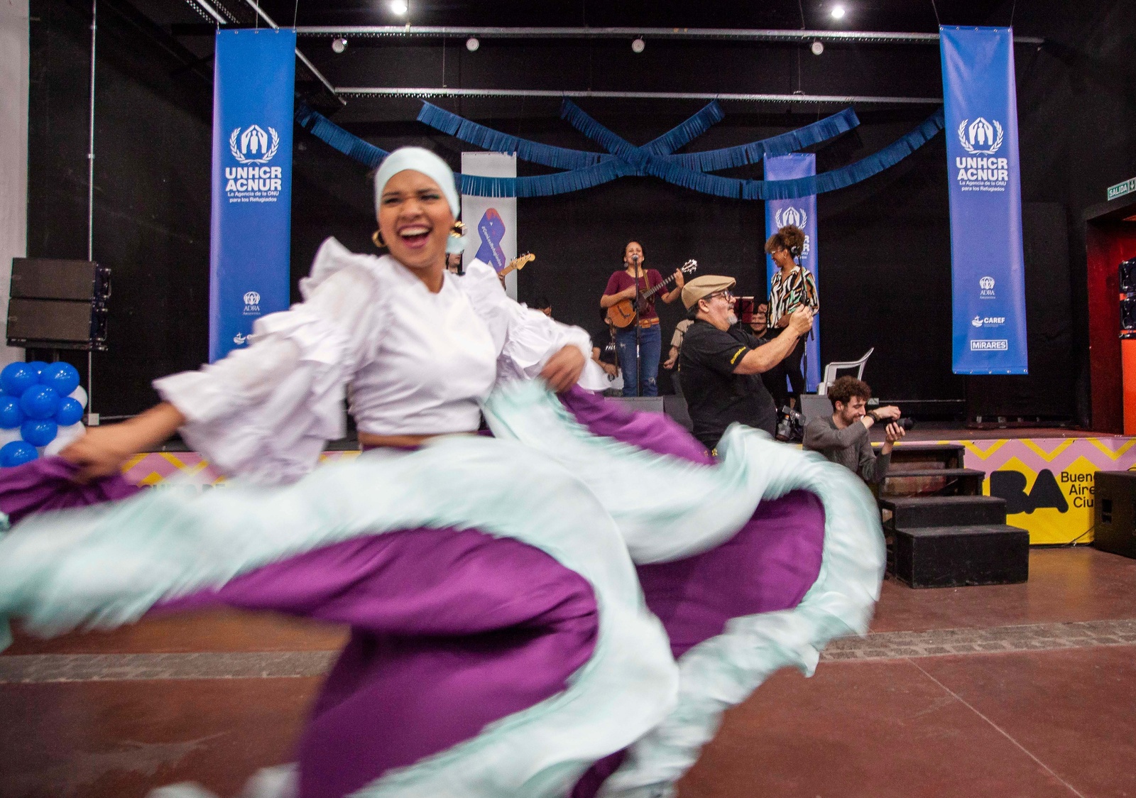 Una mujer con un vestido blanco con morado baila