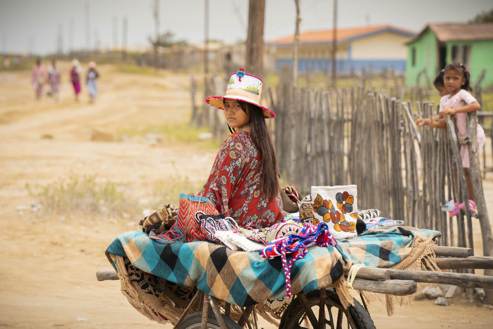 Una mujer joven sentada sobre una carretilla que usa para la venta de artesanías