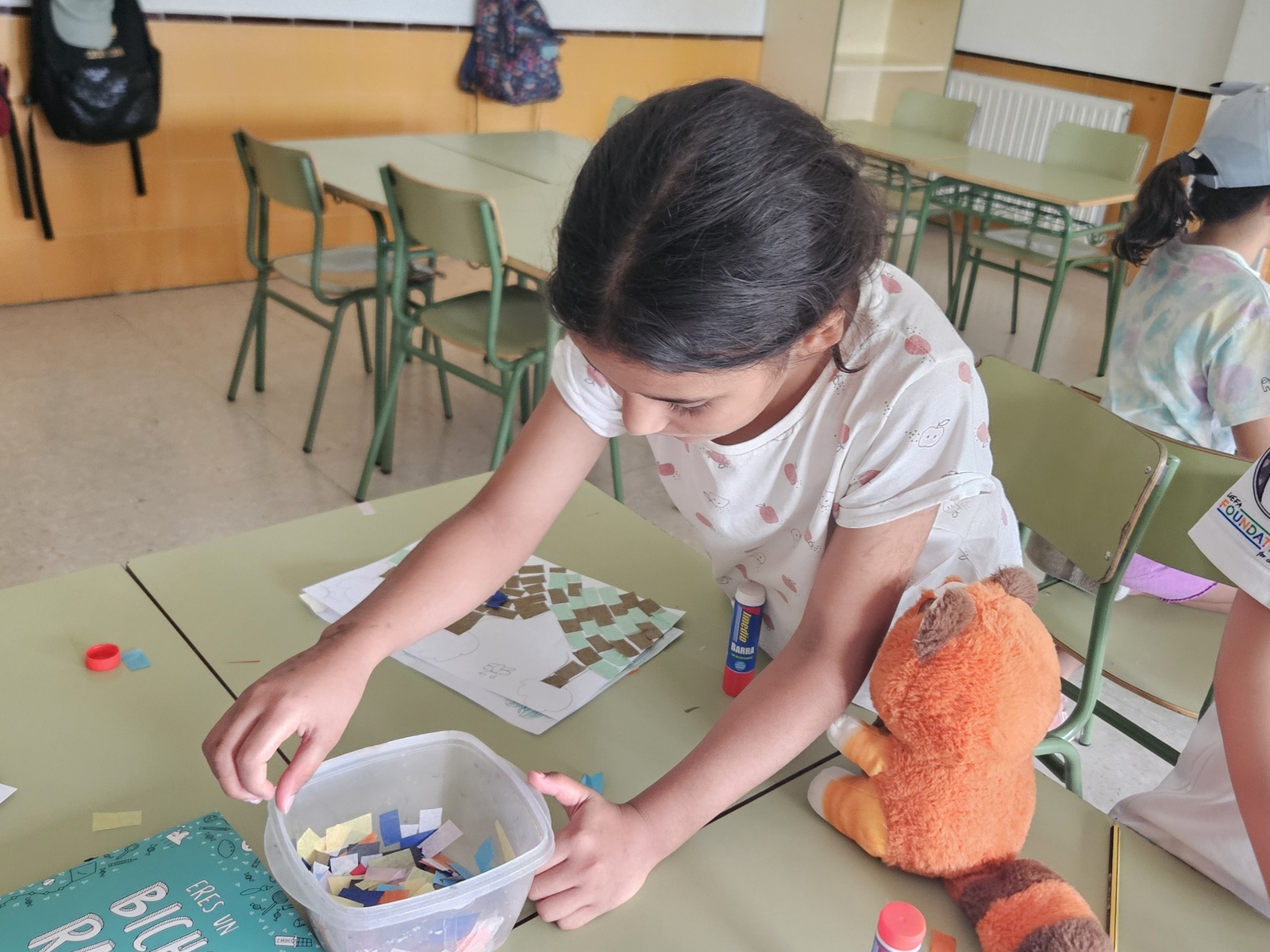 Una niña hace manualidades en un aula.