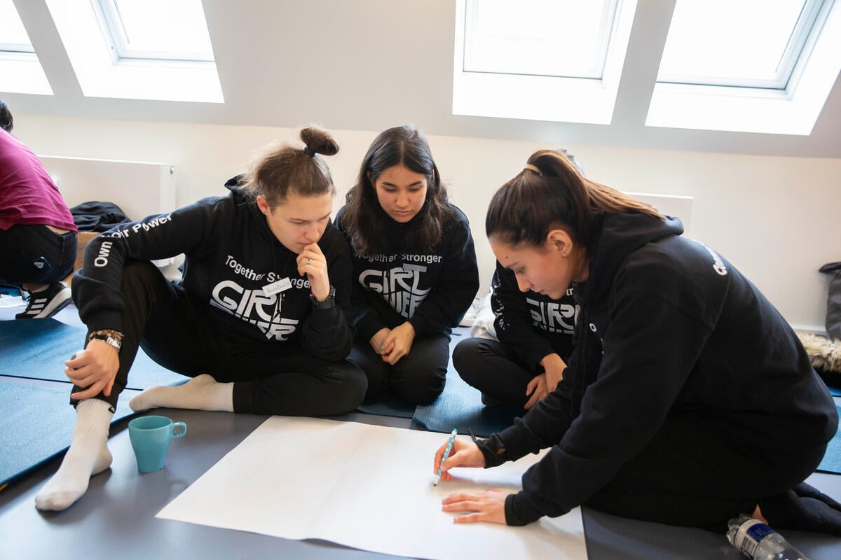 Un grupo de cuatro jóvenes trabajan en grupo en el suelo