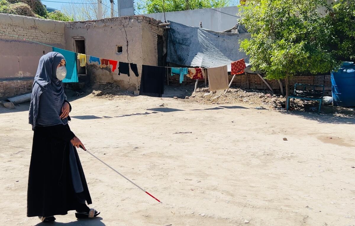 Una mujer camina con un bastón en un patio