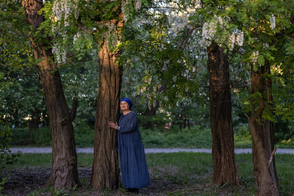 Una mujer con vestido azul abraza un árbol