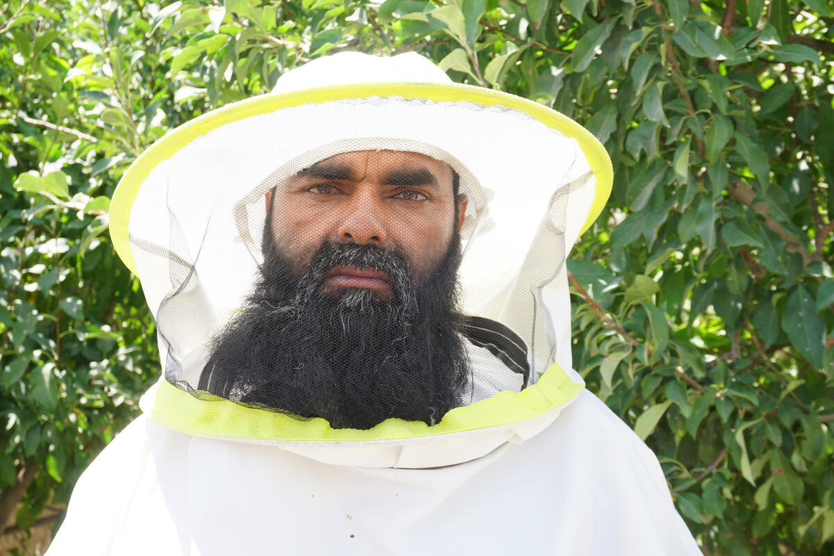 Un hombre con barba vestido con un traje blanco de apicultor