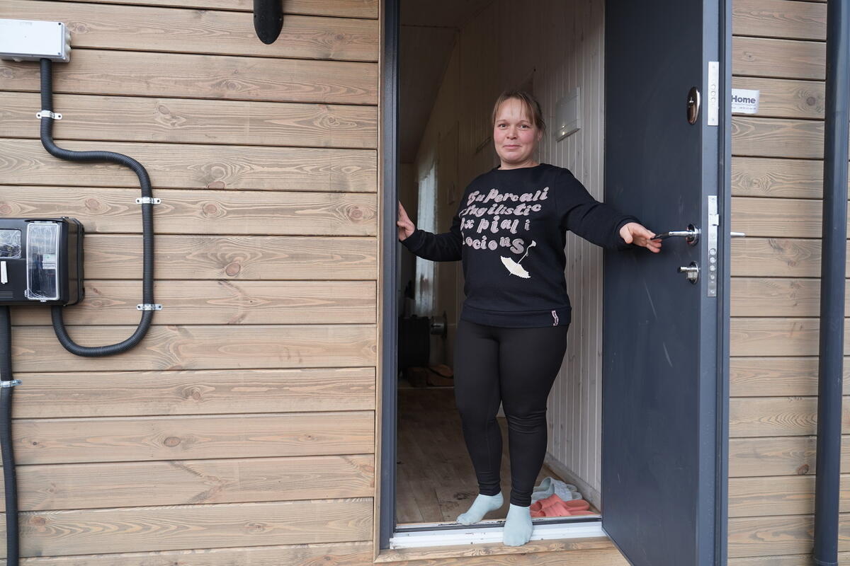Una mujer en la puerta abierta de una casa prefabricada revestida de madera