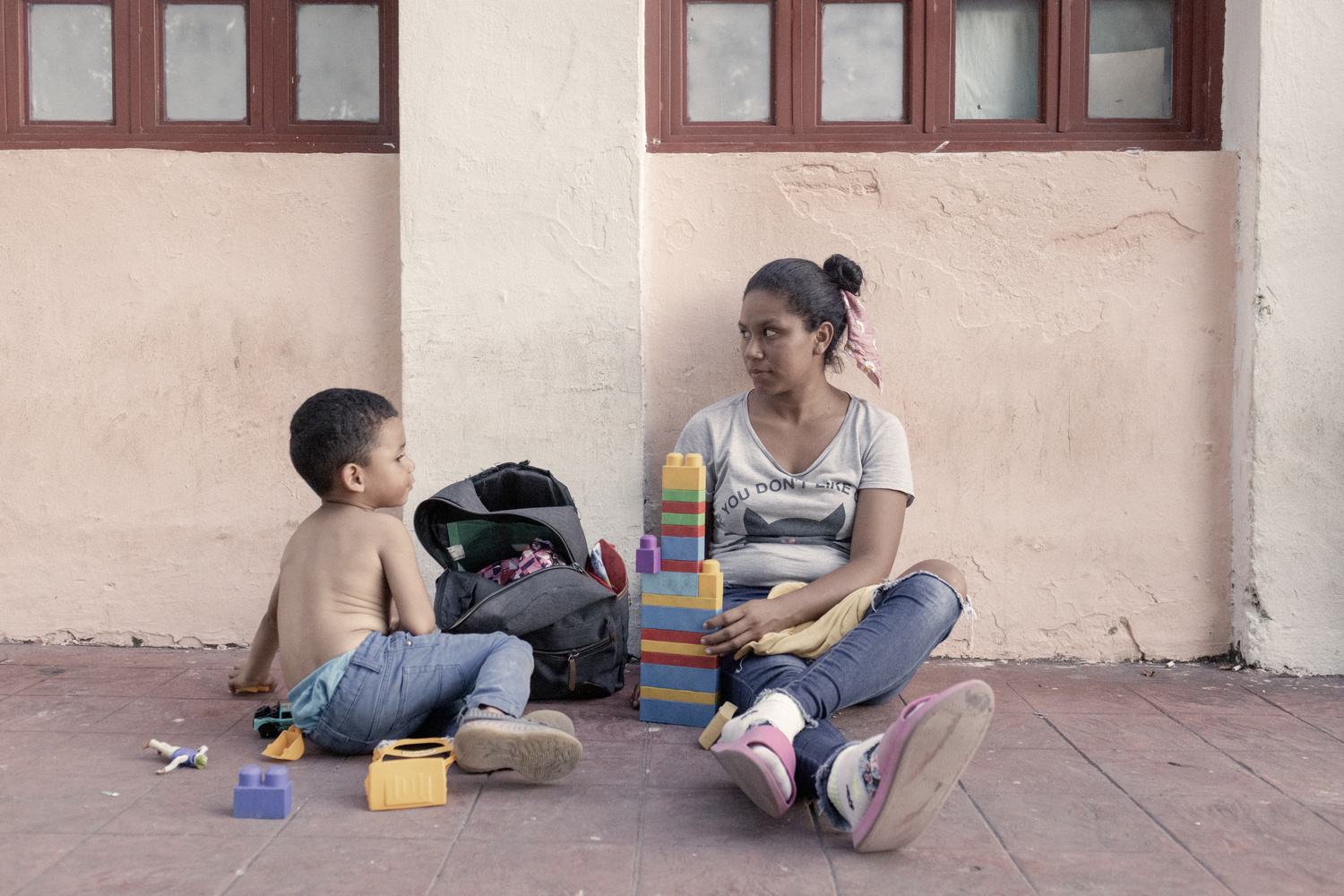 Una mujer y un niño están sentados en el suelo jugando con piezas de lego.