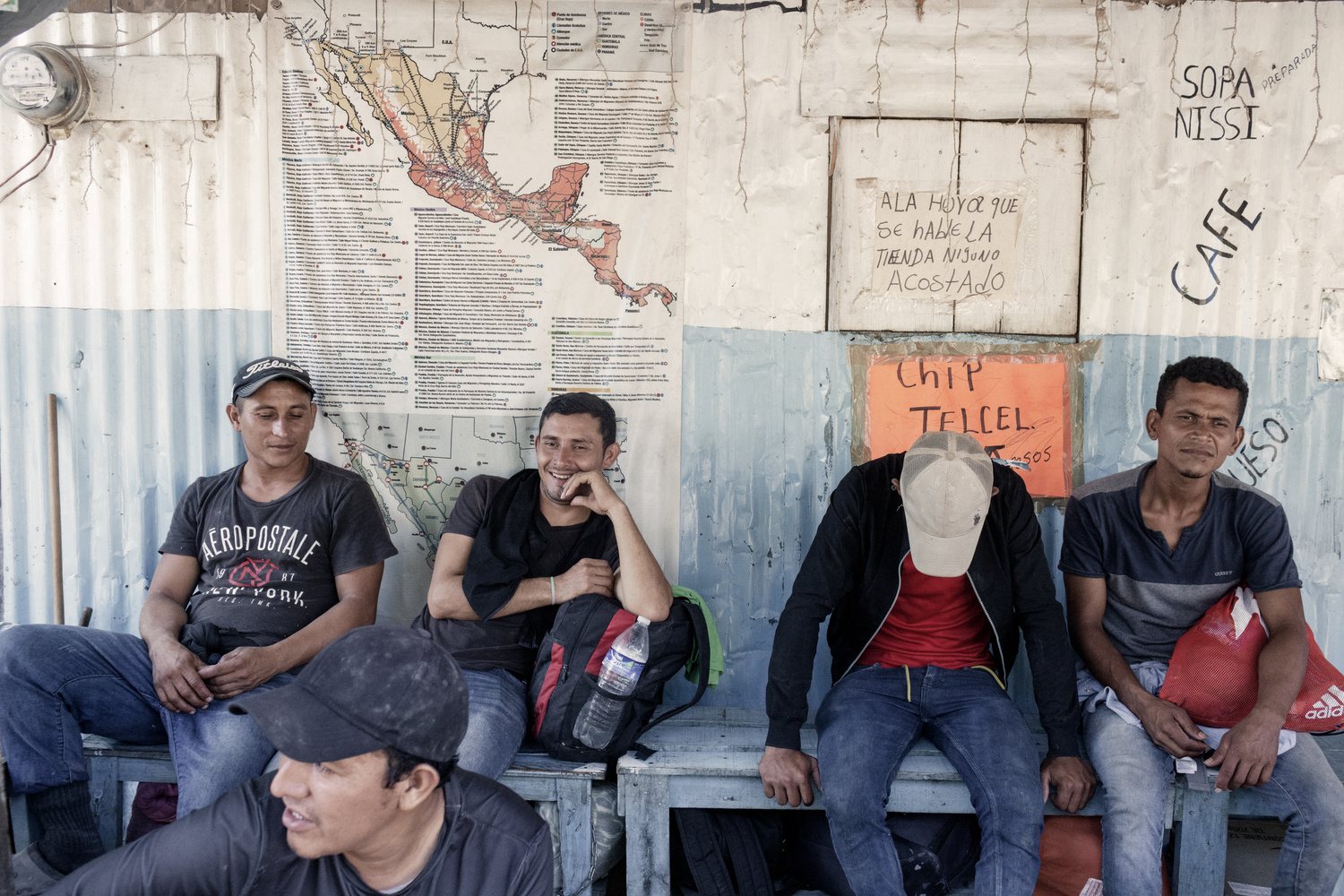 Hombres sentados en un banco frente a un mapa de México.