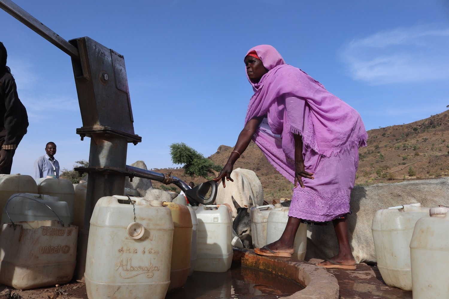 Una mujer llena recipientes con agua de un grifo en una aldea de Darfur Central.