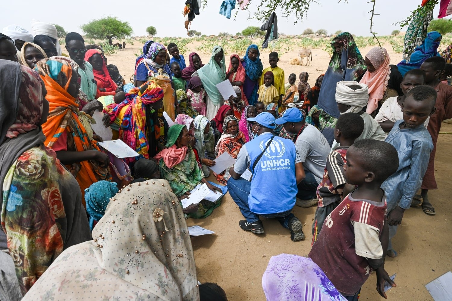 UNHCR staff members are surrounded by a crowd of Sudanese refugees in Chad. 