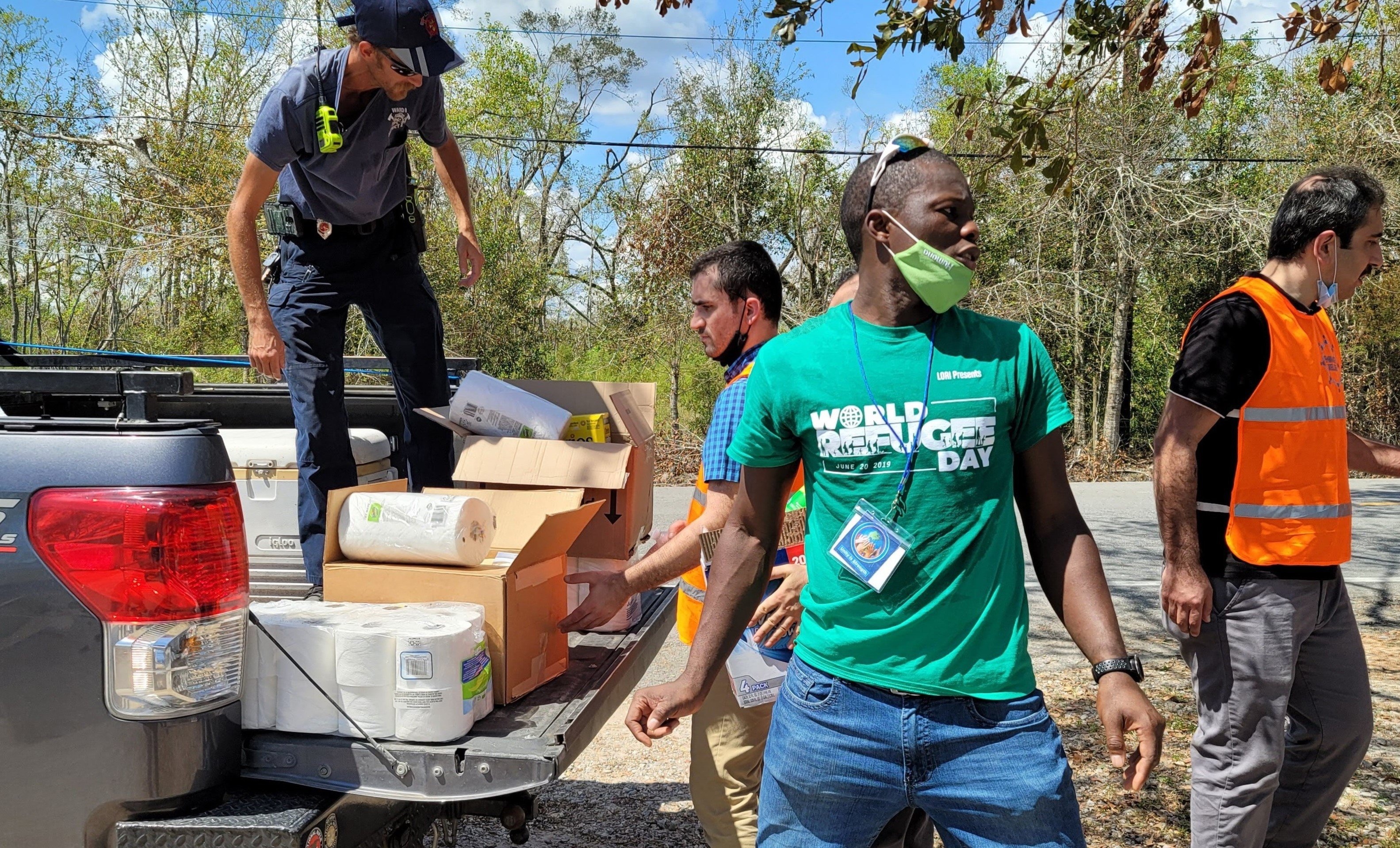 Un grupo de hombres descarga cajas de art&iacute;culos de socorro de la parte trase de una camioneta.
