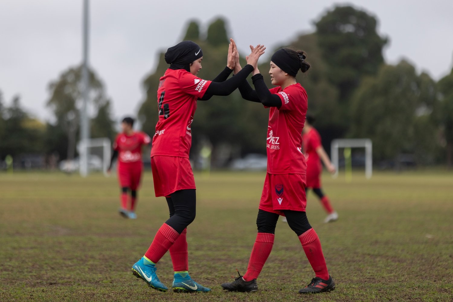 Dos chicas chocan sus palmas en una cancha de fútbol