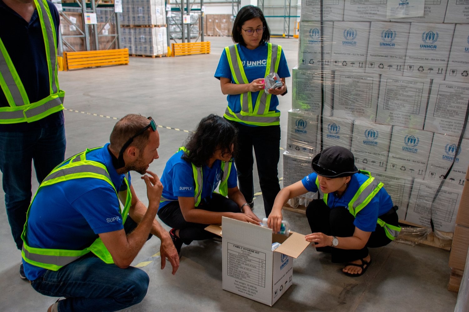 Miembros del equipo de suministros inspeccionan el contenido de un kit de higiene familiar.