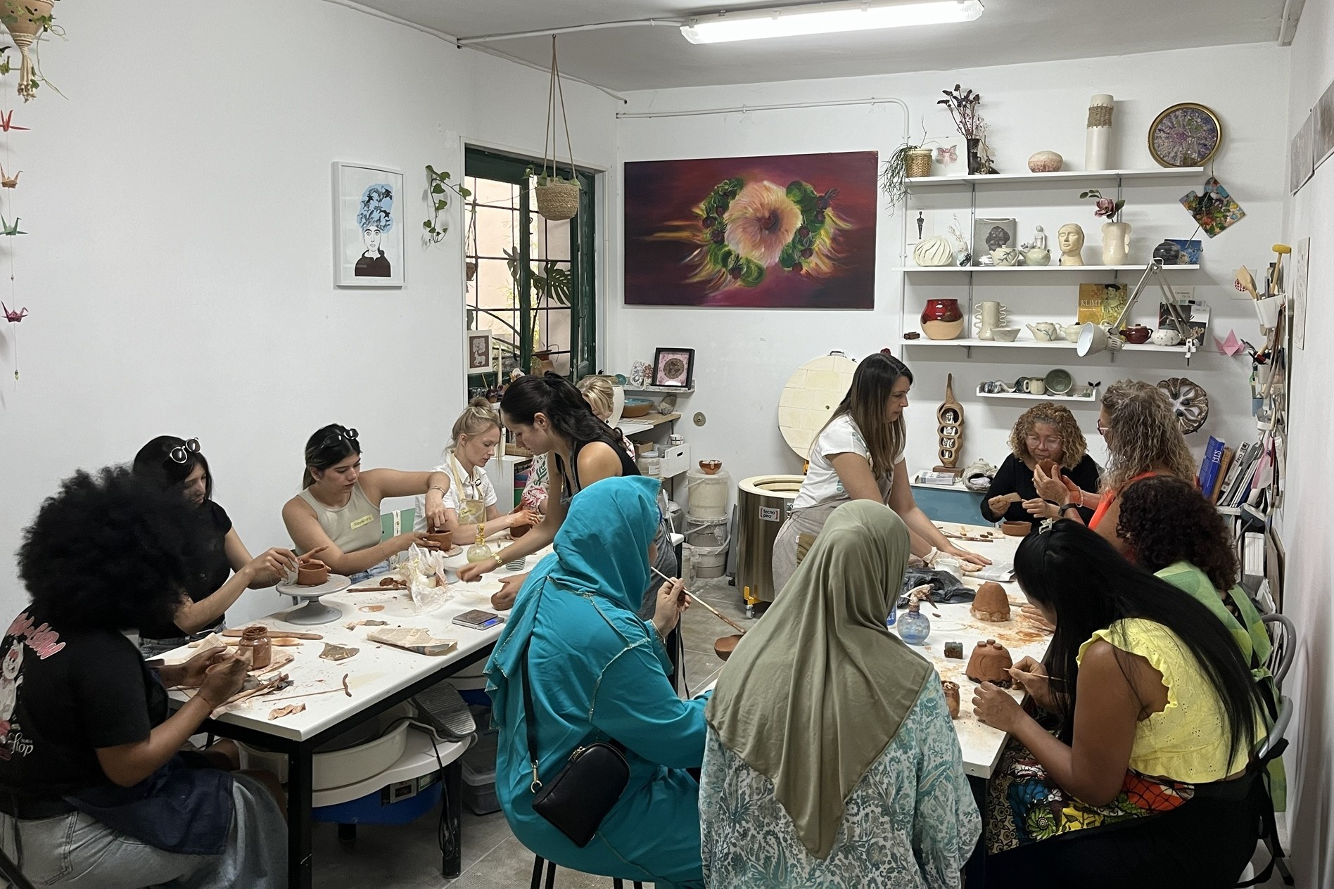 Un aula de clases de cer&aacute;mica con un grupo de mujeres sentadas modelando arcilla.
