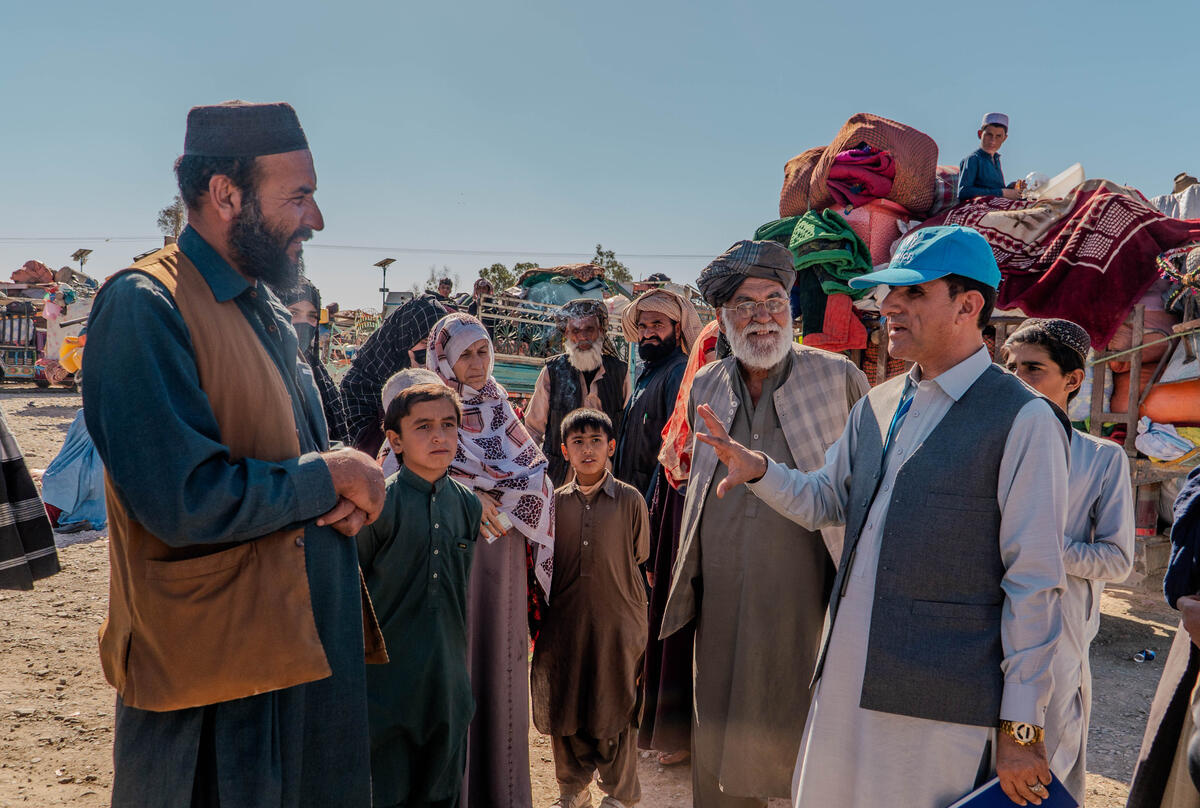 Assadullah (a la izquierda) habla con un miembro del personal de ACNUR tras llegar a Spin Boldak con su familia. Vivió en Pakistán por más de 40 años.