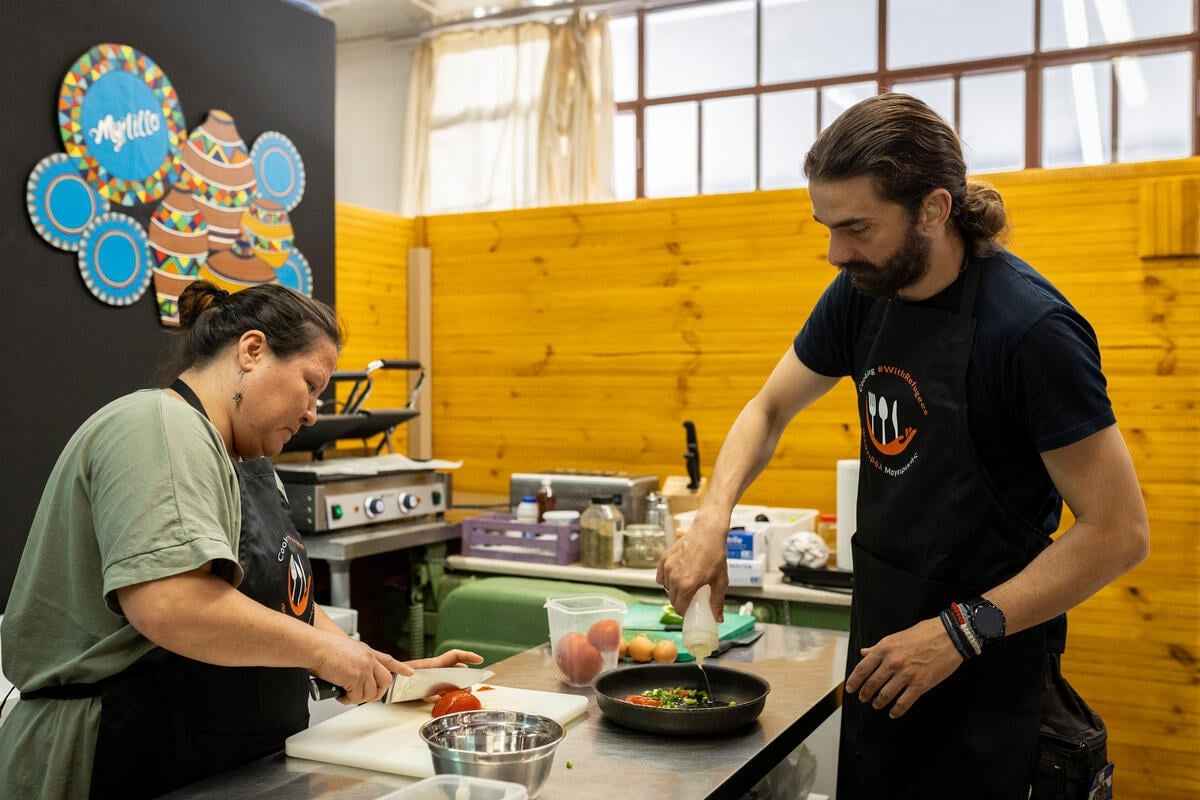 Una mujer y un hombre con delantales preparan alimentos en una cocina
