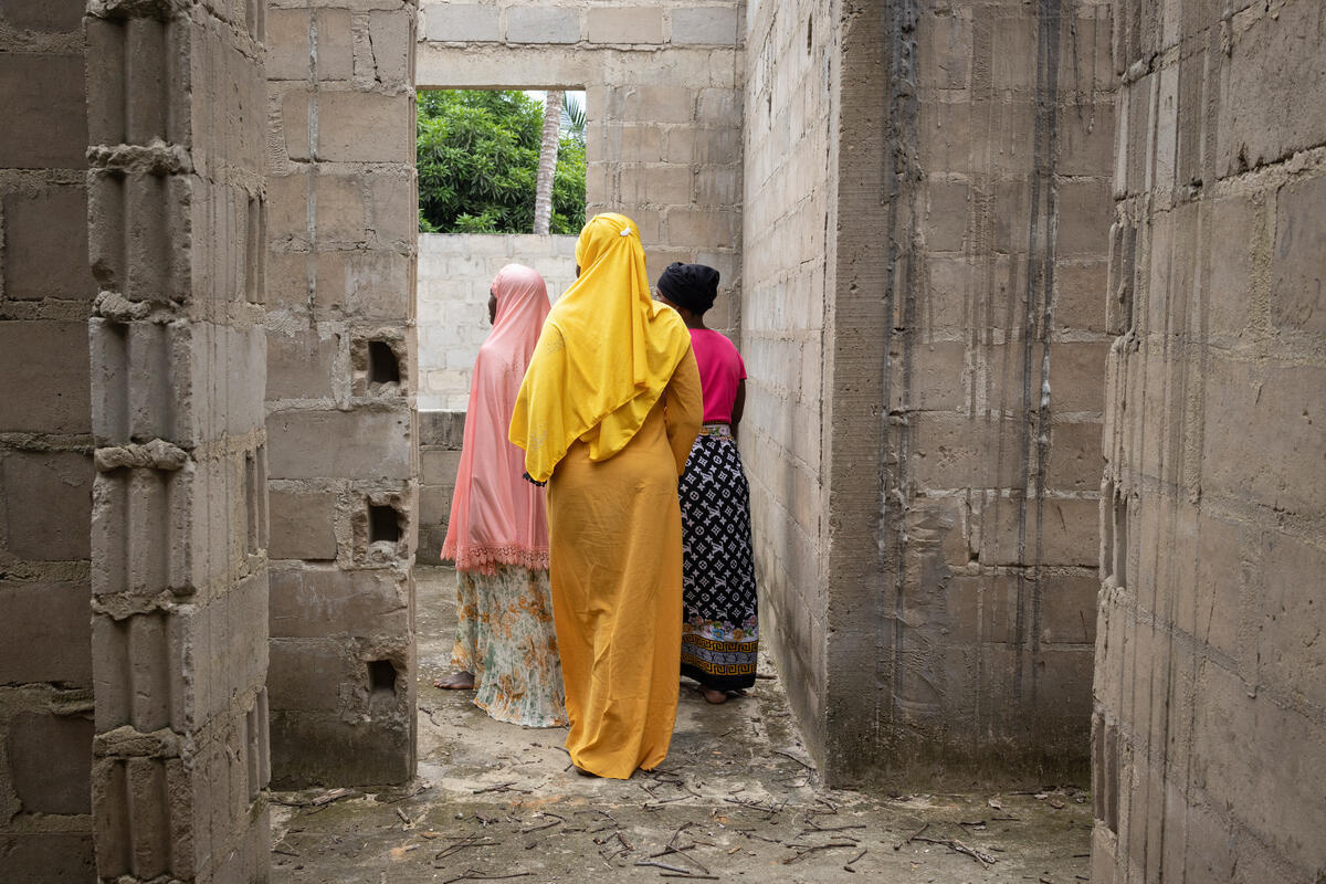 Tres mujeres caminan por un edificio abandonado de espaldas a la cámara
