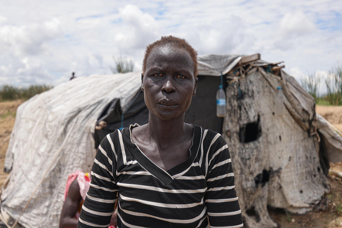 Aduot Wuoi Monjuon, desplazada interna, posa junto a su refugio en Bor, Sudán del Sur, donde se ha desplazado después de que las inundaciones la obligaran a huir de su aldea en el Estado de Jonglei, junto a su familia.