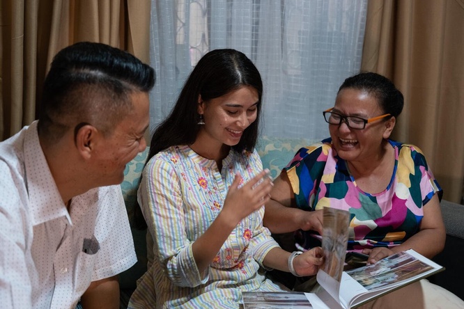 Una familia nepalí (la madre, a a derecha; la hija, al centro; el padre, a la izquierda) está sentada viendo un ábum de fotos