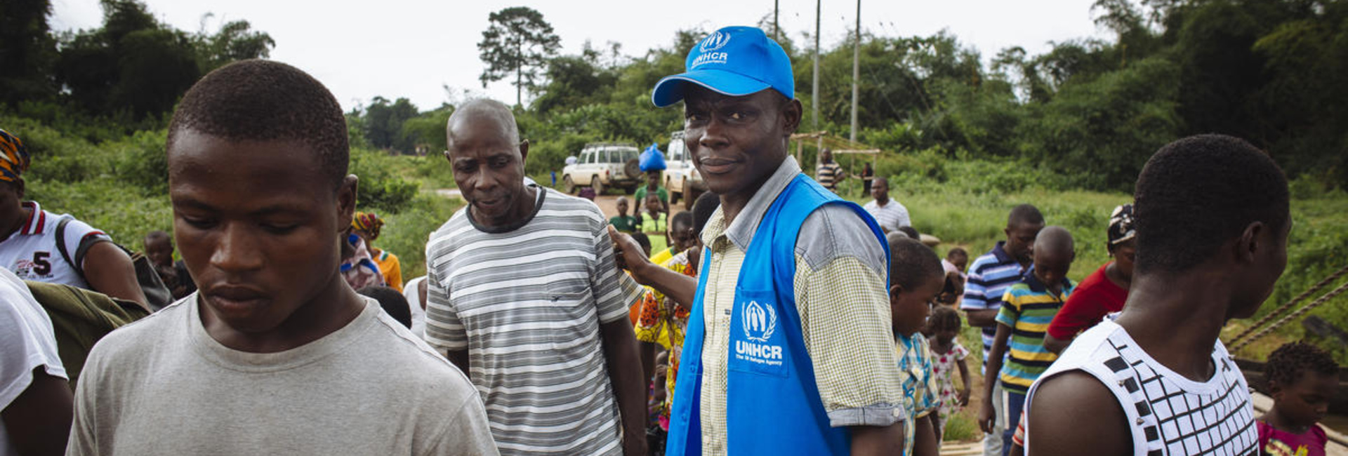 Un trabajador de ACNUR ayuda a un grupo de personas refugiadas a abordar un ferry que las llevará de vuelta a Côte d'Ivoire, su país de origen.