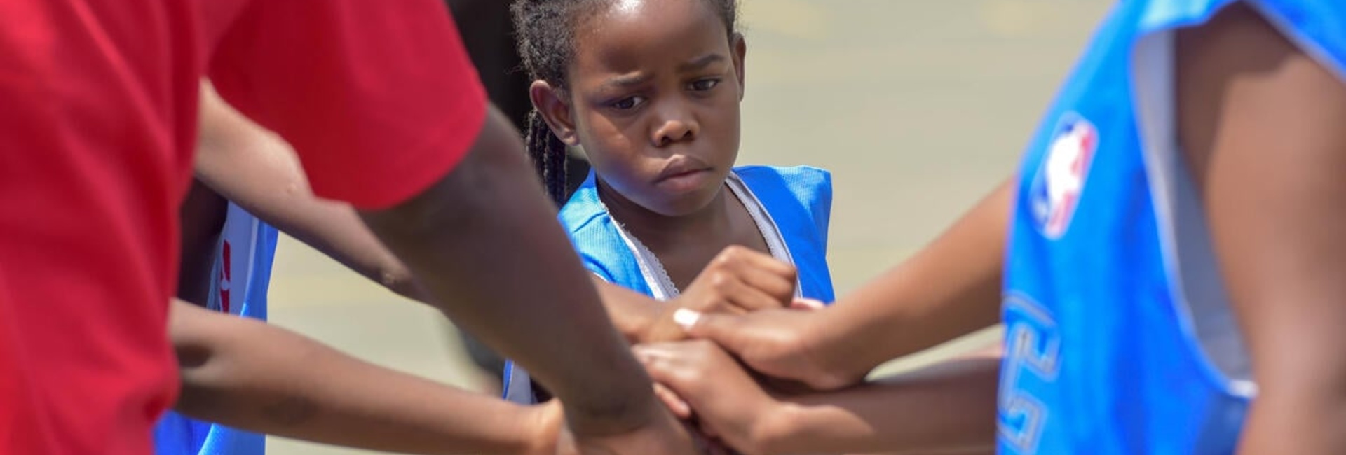 Un grupo de personas afrodescendientes unen sus manos con las de una niña que lleva puesto un chaleco azul