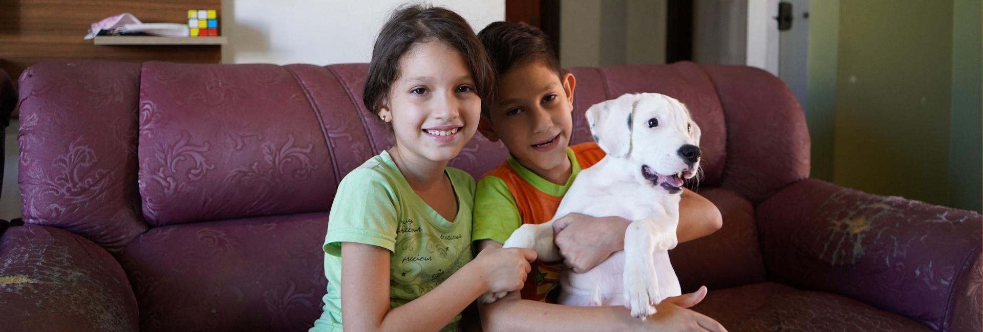 Una niña y un niño abrazan a su mascota