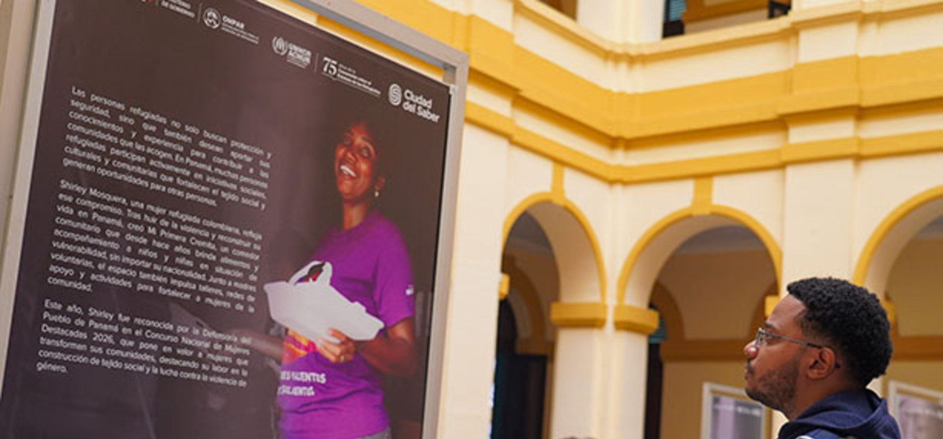Un joven mirando un panel fotográfico y textual en una exposición.