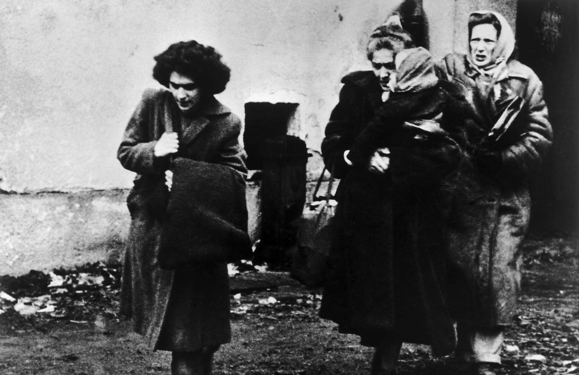Fotografía en blanco y negro de tres mujeres con un niño que llegan a un campamento de refugiados en Austria