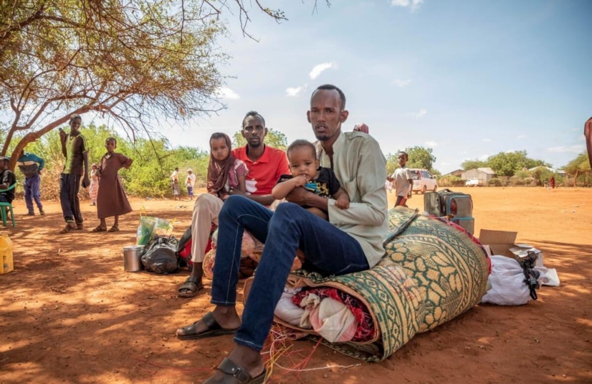 Refugiados somalíes esperan sentados debajo de un árbol.