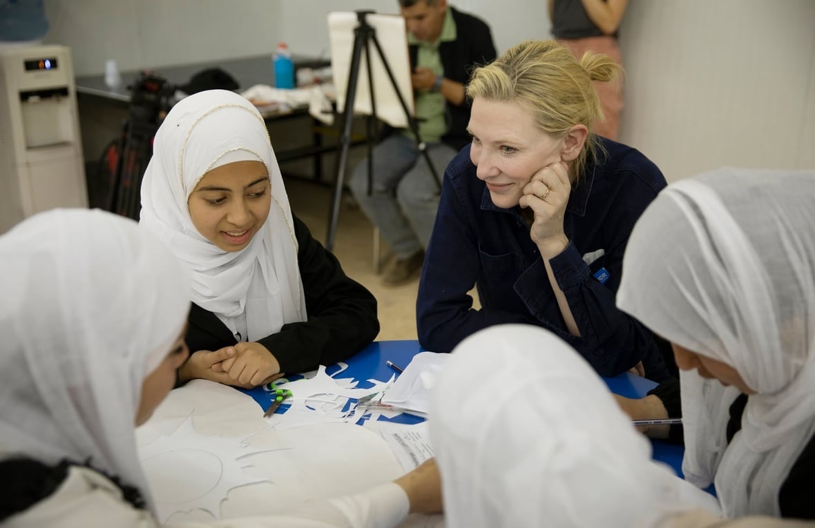 un grupo de niñas sentadas a una mesa junto a Cate Blanchett.