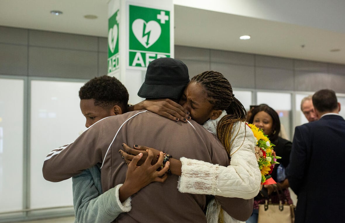 Tres personas se abrazan en un aeropuerto