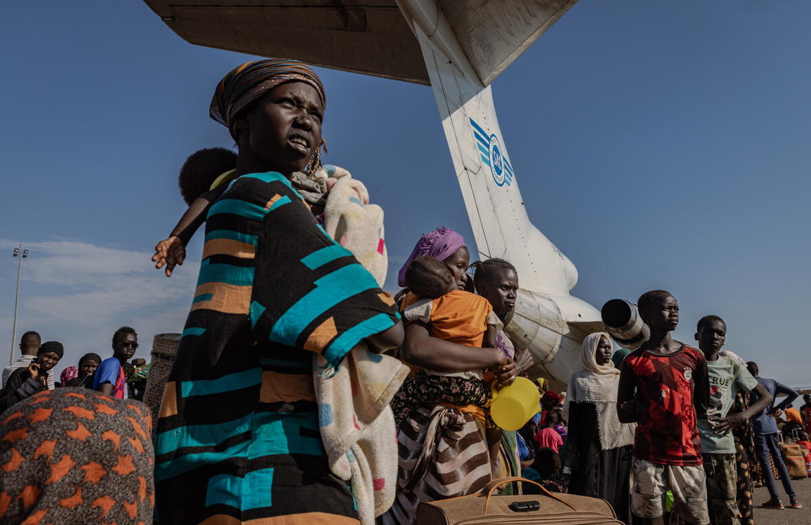 Un grupo de personas retornadas espera abordar los aviones que las llevarán a distintas partes de Sudán del Sur