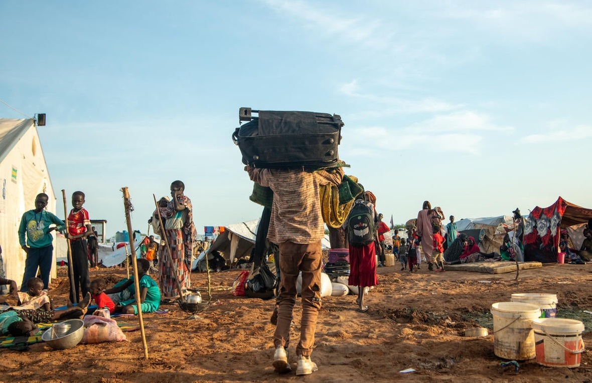 Un niño ayuda a sus padres a llevar sus pertenencias al Centro de Tránsito de Renk, en Sudán del Sur, tras cruzar la frontera huyendo del conflicto en Sudán.