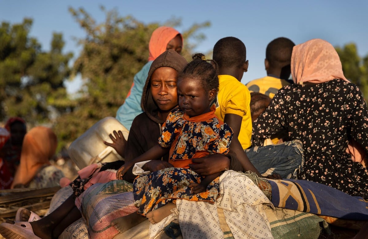 Un grupo de mujeres y niños viajando en parte trasera de una carreta.