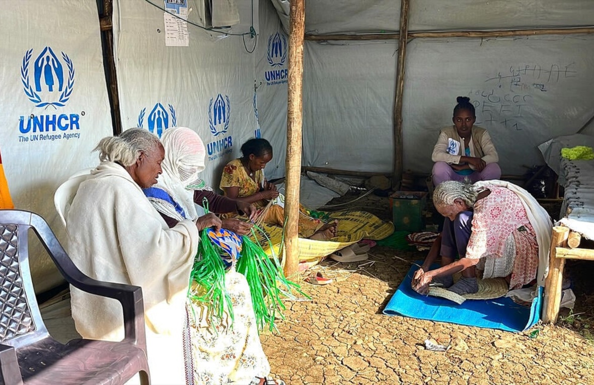 Varias mujeres sentadas en una tienda de ACNUR tejen artesanalmente