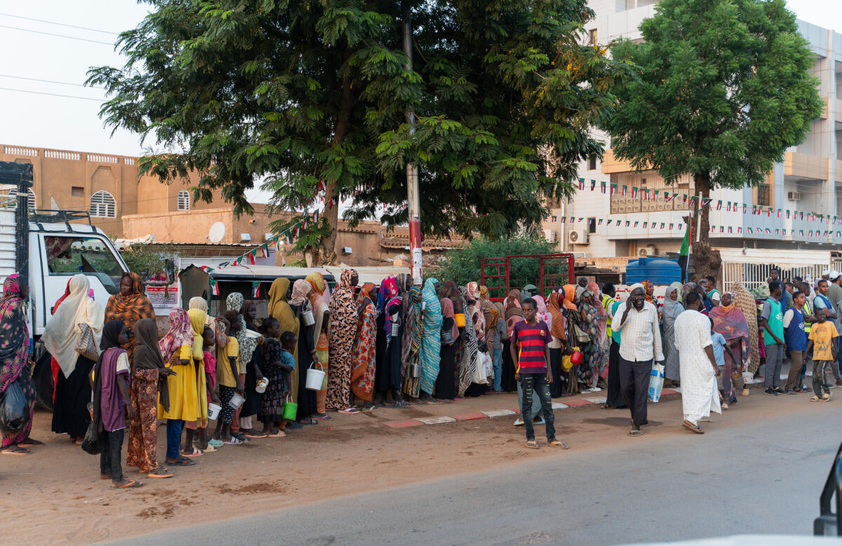 Familias desplazadas recientemente de El Fasher hacen fila en un reparto de alimentos, junto a residentes de larga duración, en Omdurman, la segunda mayor ciudad de Sudán.