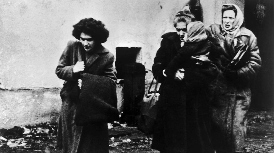 Fotografía en blanco y negro de tres mujeres con un niño que llegan a un campamento de refugiados en Austria