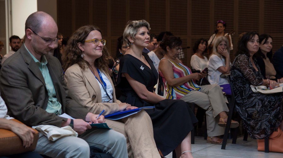 Un hombre y dos mujeres sentados, atienden un evento