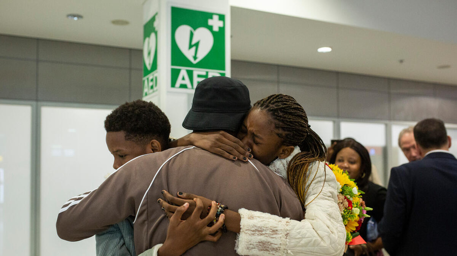 Tres personas se abrazan en un aeropuerto