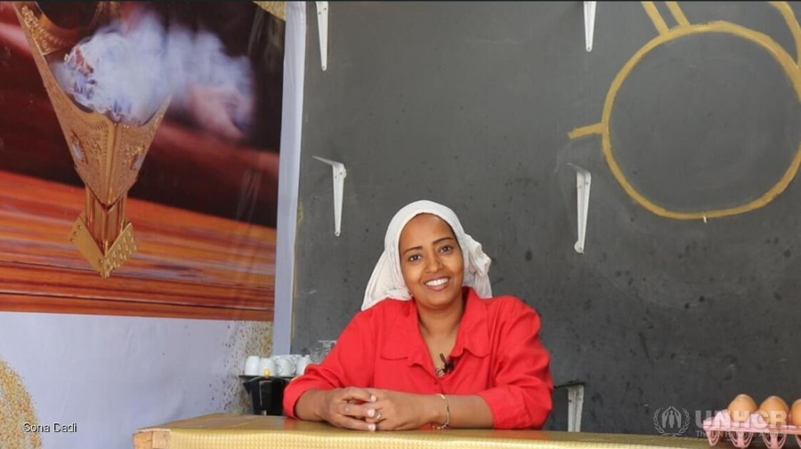 Una mujer con una camisa roja brillante detrás del mostrador de una cafetería.